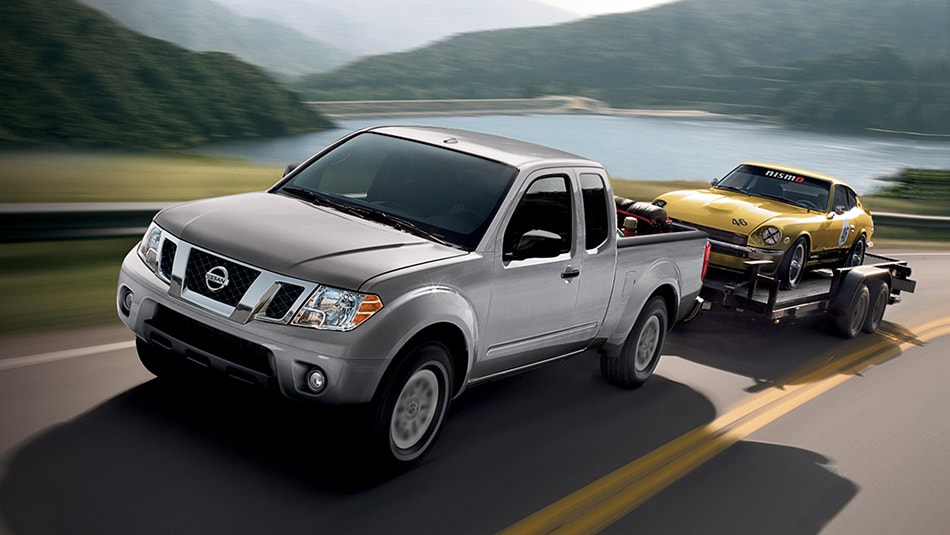 Silver 2015 Nissan Frontier King Cab Towing Trailer with Yellow Classic 240z