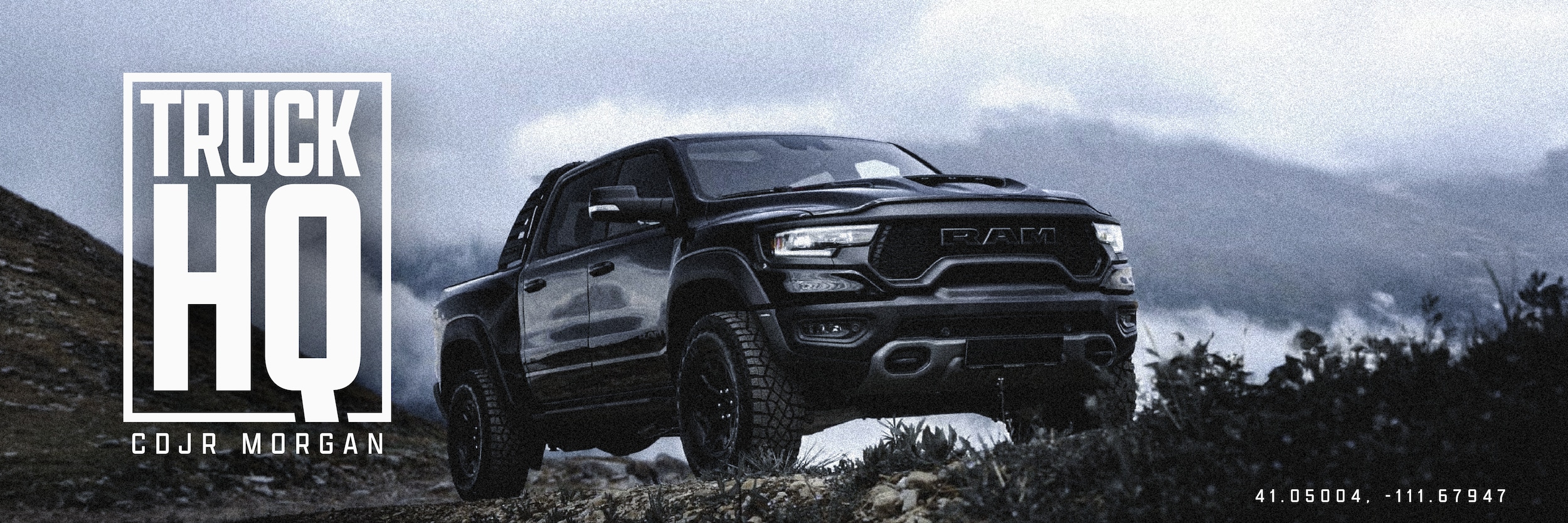 Black RAM truck parked on a rocky ridge under storm clouds
